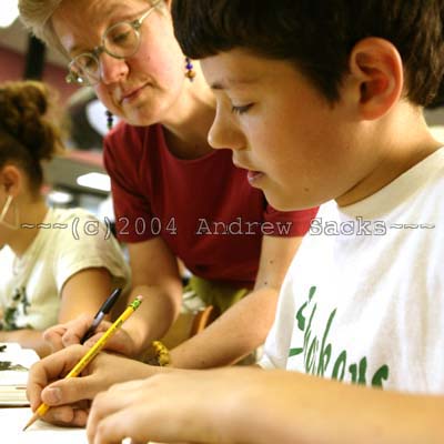 Elementary school teacher helps boy at desk 